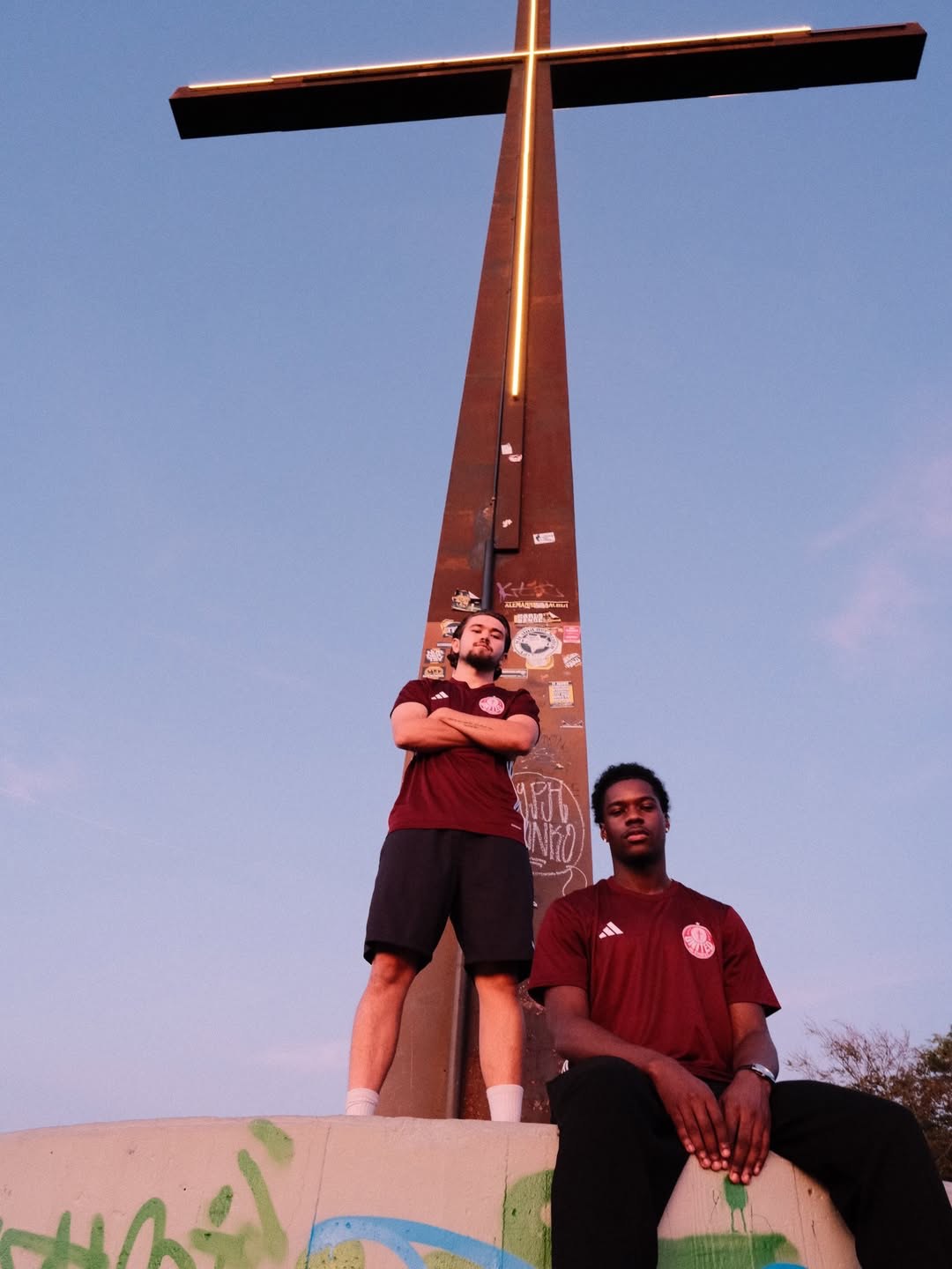 Zwei Spieler in bordeauxroten United-in-Christ-Trikots am Kreuz